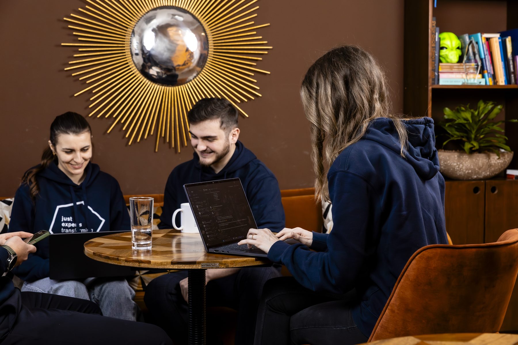 Drei Kolleg:innen von just experts arbeiten gemeinsam an einem Tisch